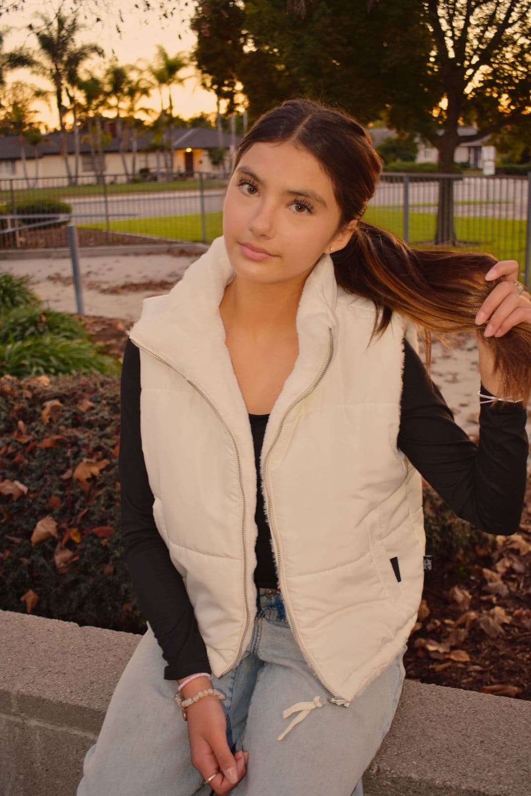 A teenage girl in a cream puffer vest photographed outdoors at dusk in Las Vegas, NV