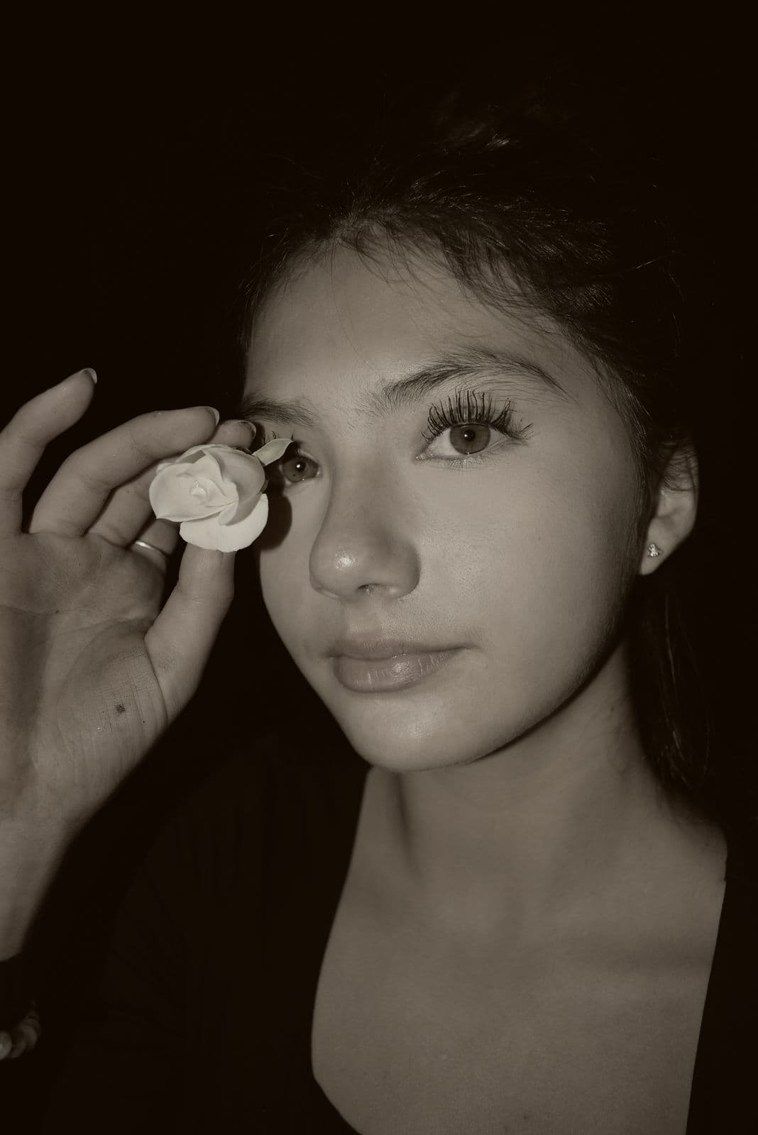 A black-and-white close portrait of a teenage girl holding a small flower, Las Vegas, NV