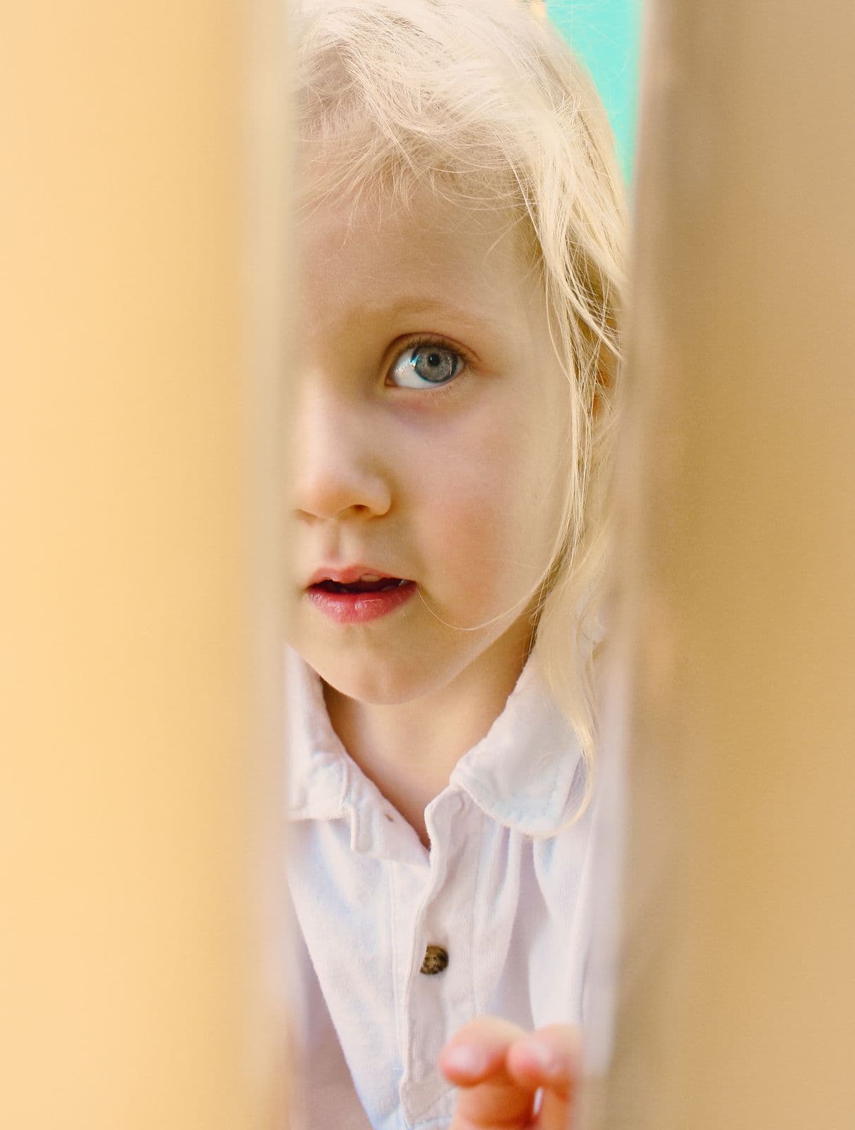 A small blonde child peeking around a wall during a family photo session in Las Vegas, NV