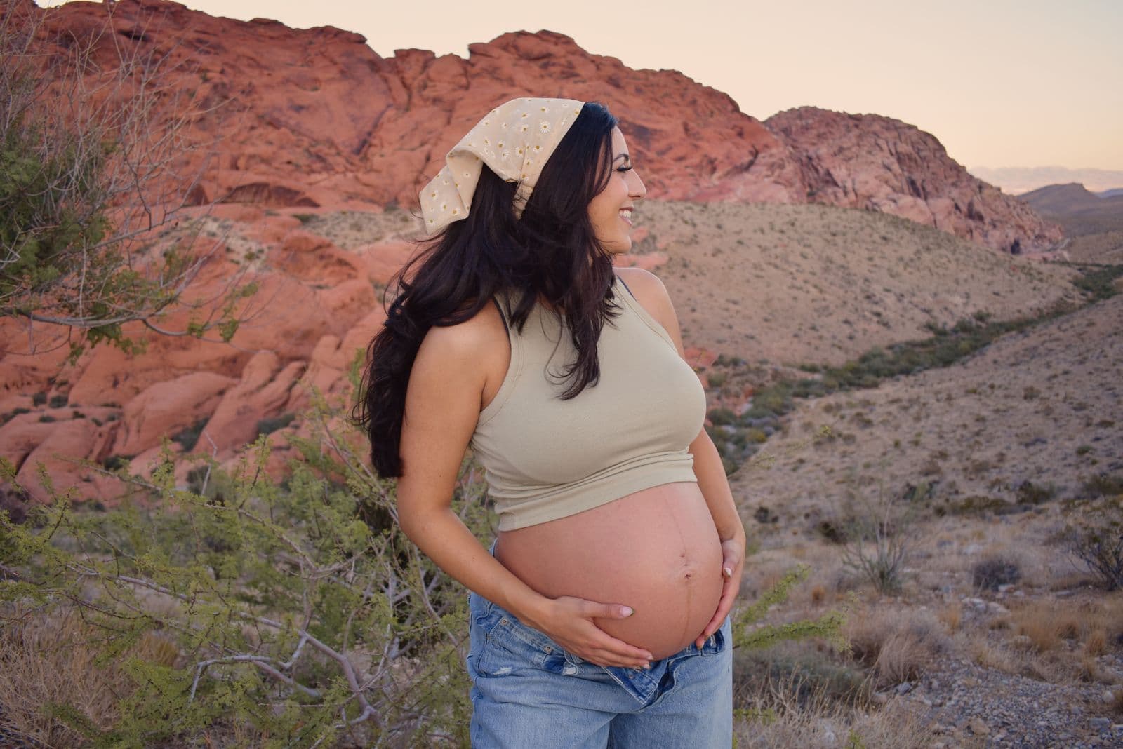 An expecting mother in a lace head scarf standing in profile against the red cliffs of Red Rock Canyon near Las Vegas