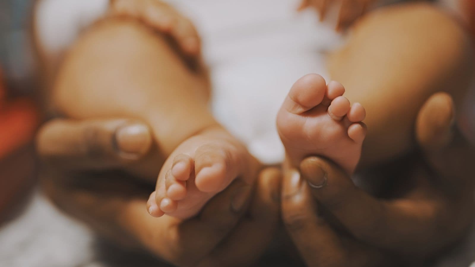 A close detail of a newborn's feet cradled in a parent's hands during an in-studio newborn session in Las Vegas, NV
