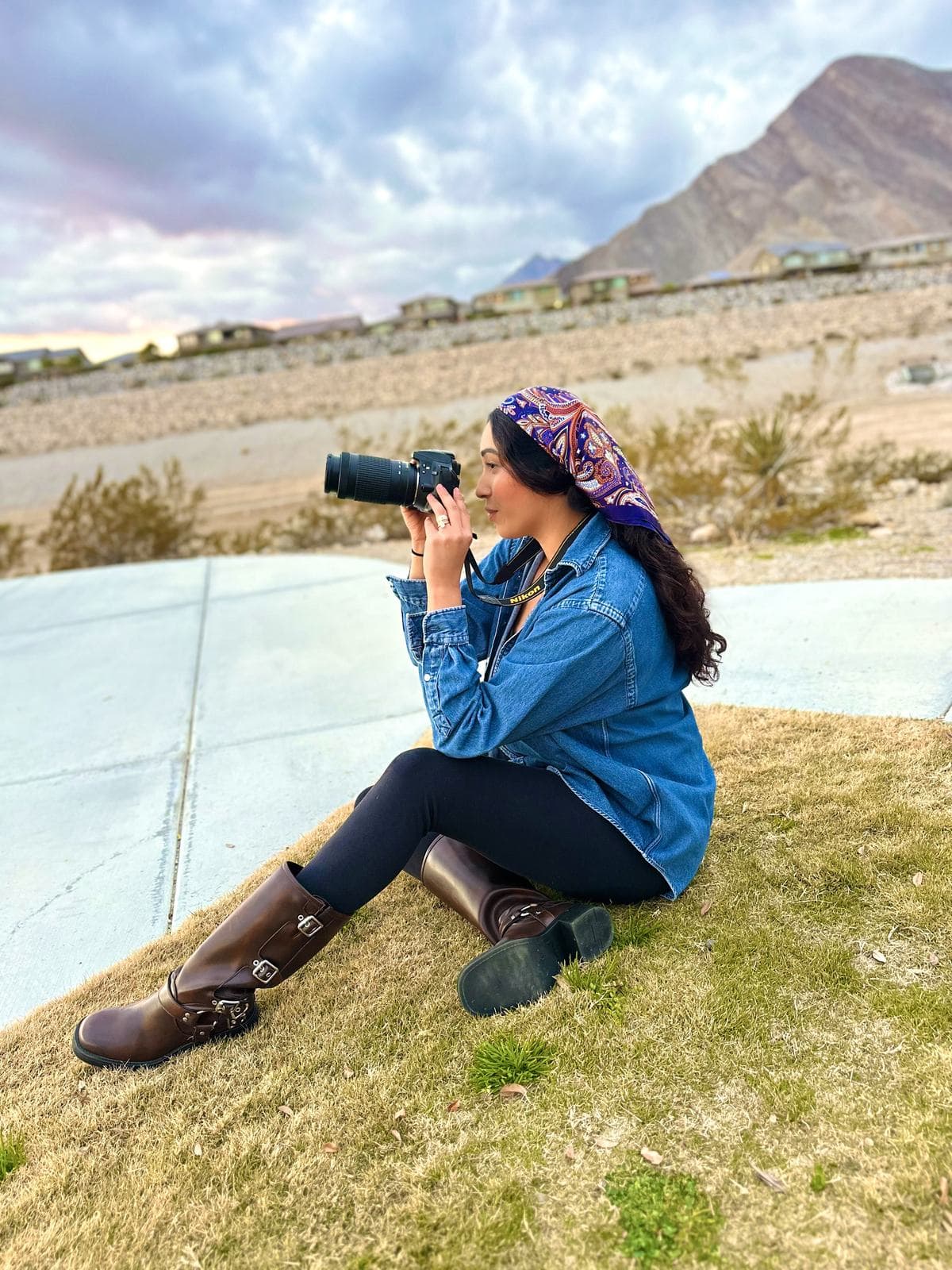 Melyssa Silva photographing at golden hour on the edge of the Las Vegas valley, camera raised toward the mountains as the sun sets